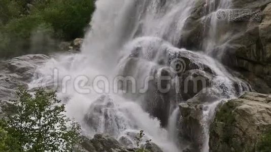 慢动作的水从一块巨大的岩石上掉下来。 阴天有小雨的自然环境中的瀑布视频