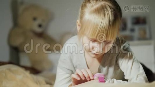 一个女孩正在玩她手臂上的智能时钟。 躺在卧室的床上视频