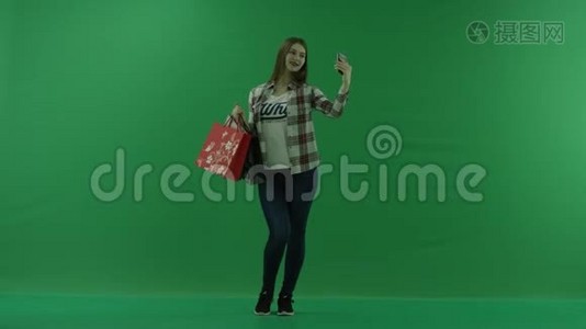 女孩带着购物袋，站在半个转弯处，向右看，在绿色屏幕上自拍视频