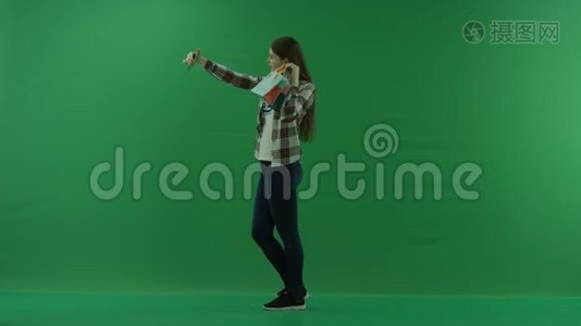 带迷你包的女孩站在左边，在绿色屏幕上自拍视频