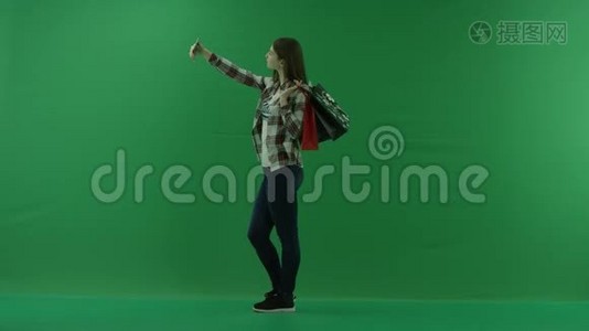 女孩肩上扛着购物袋，站在左边，在绿色屏幕上自拍视频