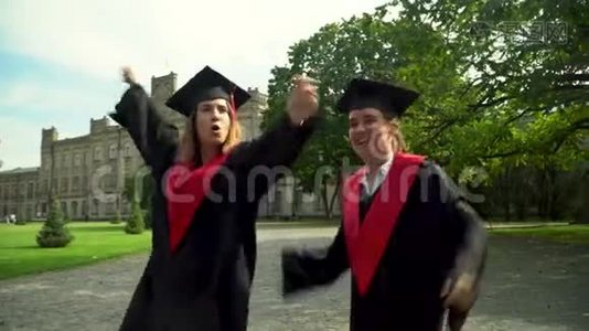 两个快乐的学生穿着黑色和红色的壁炉庆祝他们在大学大楼前毕业。 二.视频
