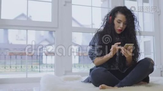 红唇迷人的黑发女郎用耳机听音乐，用电话视频
