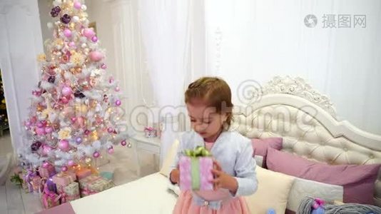 小女孩新年快乐，跳床在儿童房`粉红背景圣诞树与玩具。视频
