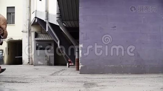 在城市后院的紫墙边走着的人。视频