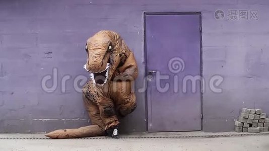 穿着雷克斯吉祥物服装的人站在紫色墙上的门旁视频