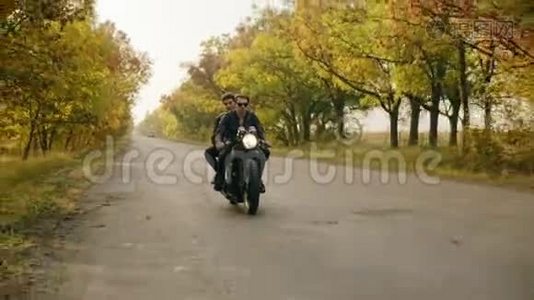 戴墨镜的帅哥骑着摩托车，女朋友跟在后面，一起在柏油路上旅行视频