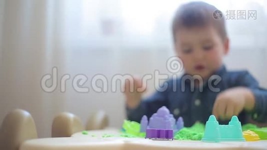 美丽的小男孩雕刻在绿色动力的沙堡和形状视频