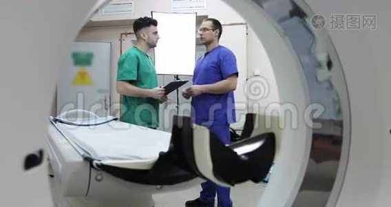 4两位年轻的医生用CT扫描仪在房间里讨论病人的治疗。视频