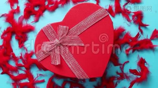 红色的心形礼品盒放在红色羽毛的蓝色背景上视频