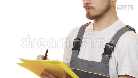 一名工业工人在剪贴板上微笑着做笔记的被裁剪的镜头视频