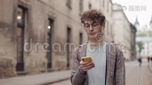 戴着眼镜的年轻潮人使用现代智能手机与朋友在社交网络聊天，听音乐视频