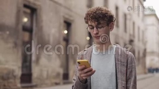 戴着眼镜的年轻潮人使用现代智能手机与朋友在社交网络聊天，听音乐视频
