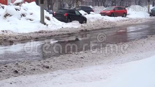 大雪纷飞的城市里，车流如潮的汽车在路上穿过一个水坑视频