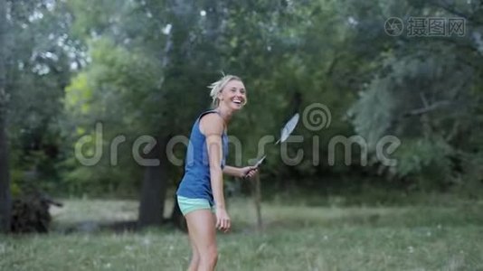 漂亮的微笑，运动健身女人在公园打羽毛球。视频
