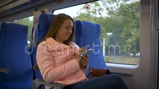 年轻的美女坐在火车的副驾驶座上，在智能手机上发短信视频