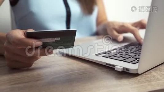 网上购物概念。 女人手拿信用卡，用手提电脑视频