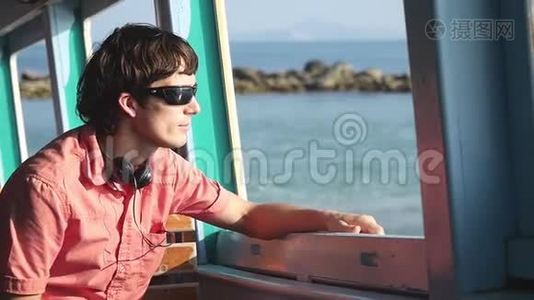 年轻的帅哥戴着太阳镜，在海上享受航海旅行。 假期概念。 慢动作。 1920x1080视频