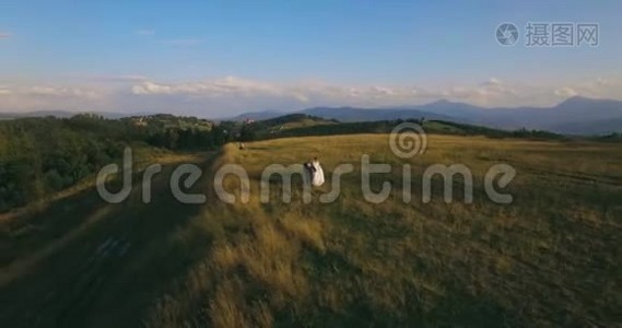 这对夫妇站在日出时风景如画的山上，天空中有4K的天空视频