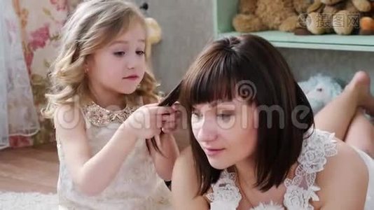 女孩正在梳理她母亲`头发，并玩它，关闭视频