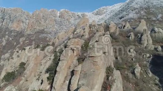 一个巨大的巨石在山坡上，靠在山顶被雪和蓝天覆盖。 中枪。 冬季视频