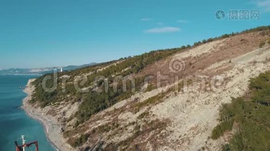 在靠近海岸线和山丘的大型货船上可以看到空中景色，沿途有人行走。 中枪。 海运视频