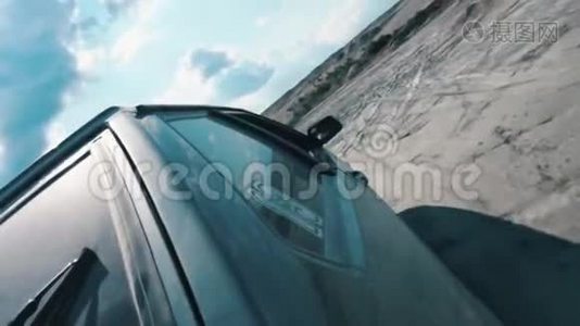 从黑色俄罗斯汽车侧面近景，在沙质的地面上，在蓝色多云的天空下行驶。 录像。 赛马比赛视频