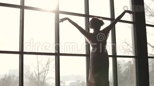 一位优雅的芭蕾舞演员的特写肖像。 窗户背景上年轻芭蕾舞演员的剪影。 慢动作视频