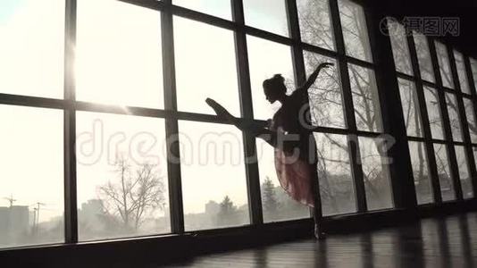 年轻的芭蕾舞演员正在大窗户前热身。 穿尖鞋的芭蕾舞演员剪影视频