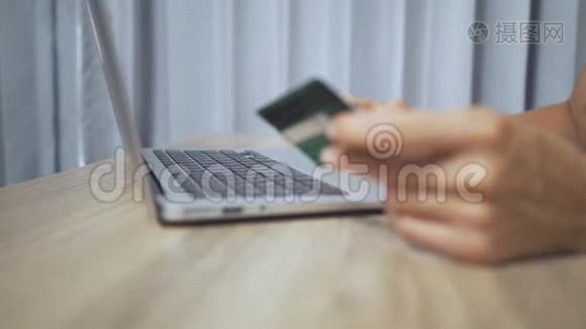 网上购物概念。 女人手拿信用卡，用手提电脑视频