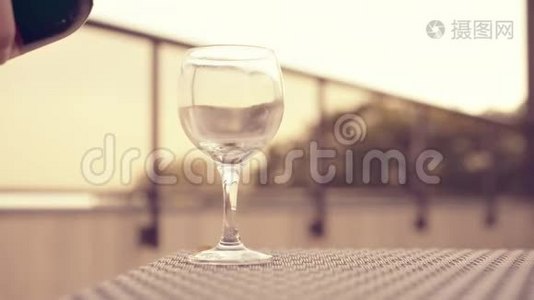 红酒倒进玻璃杯里。 有小桌子和玻璃栅栏的酒厂屋顶。 背景在软焦点。 4kUHD视频