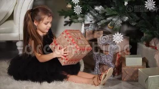 微笑的孩子，他手里拿着一个包装好的盒子，礼物坐在圣诞树下视频
