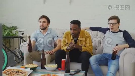一群年轻的男性朋友一起在电视上看体育比赛，一边在家喝啤酒，一边吃零食视频
