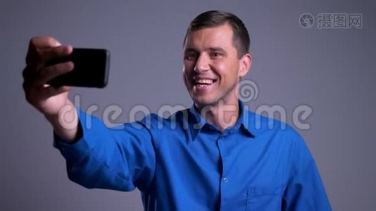 一张迷人的、快乐的高加索男人的特写照片，他在电话里打了个视频电话视频