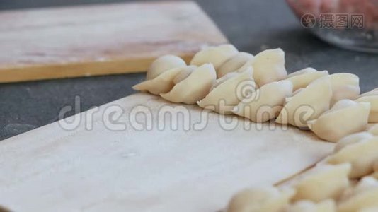 女人用肉馅包饺子，特写的手。 把饺子放在木板上。视频