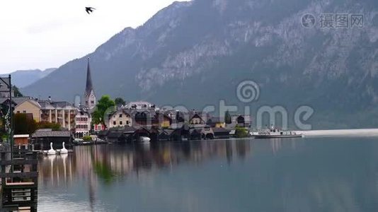 清晨，奥地利哈尔斯塔特教堂可欣赏湖景，这里有传统建筑、山脉和船只视频