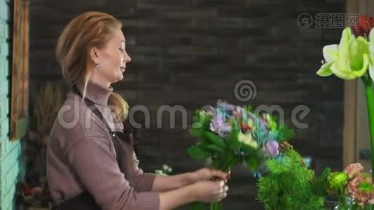 一个穿着围裙的女花匠，站在一家花店的柜台上，准备一束花。视频