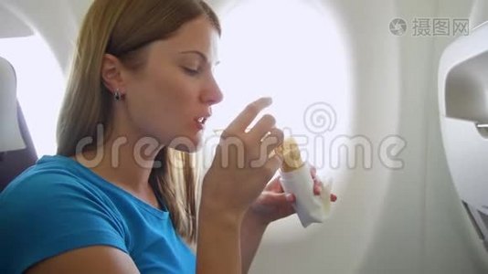 坐飞机的女人。 在湍流中，女性在靠近窗户的地方吃三明治和喝酒视频