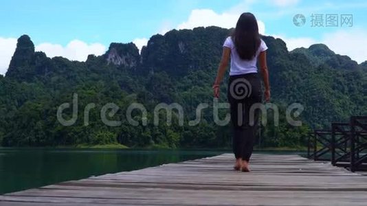 那个女孩正沿着湖边的一个木墩走。视频