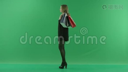 年轻女子购物后拿着袋子等待，颜色钥匙绿色背景视频