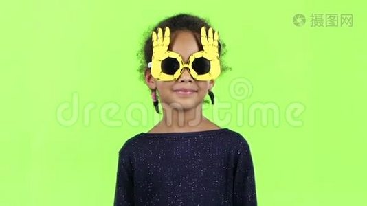 一个戴着滑稽眼镜跳舞的非裔美国女孩的孩子。 绿色屏幕。 慢动作视频