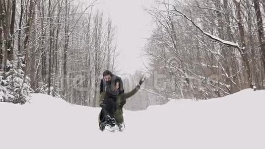 在阳光明媚的冬日里，年轻的夫妇滑着雪橇，享受着快乐。 慢动作视频