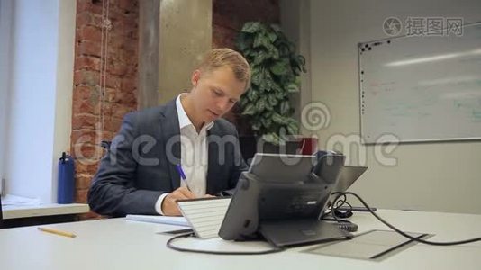 男老板坐在自己的办公室里写笔记本。视频