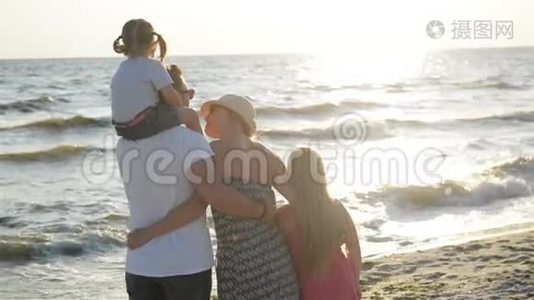 日落时分，可爱的父母和两个女儿一起在海边度过时光。 英俊的父亲视频