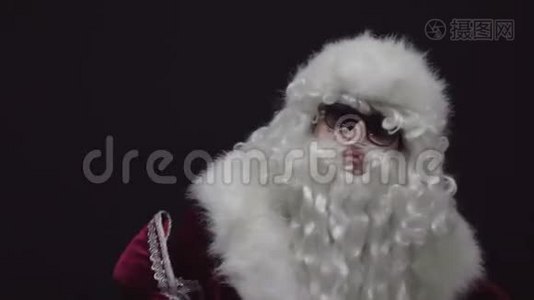 一个自信的圣诞老人的肖像，用红色圣诞老人套装折叠手臂，黑色背景。视频