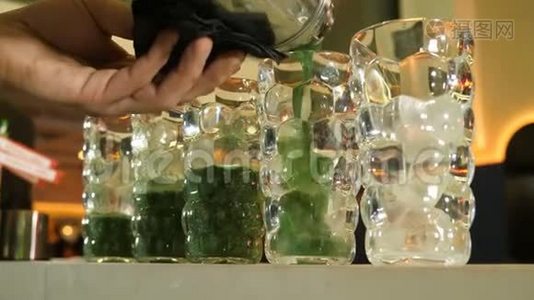 在五杯以绿色植物为基础的鸡尾酒的配制过程中，酒保会在摇床上倒一杯熟的鸡尾酒视频