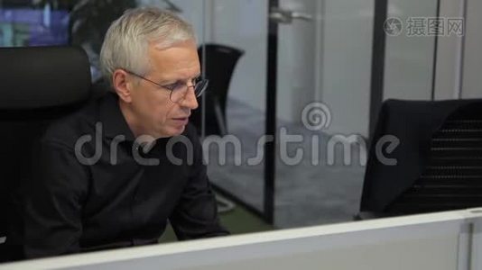 高级主管在现代办公室坐在电脑前工作。视频