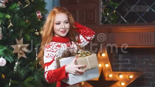 漂亮的红发女孩穿着红色毛衣，手里拿着圣诞礼物。视频
