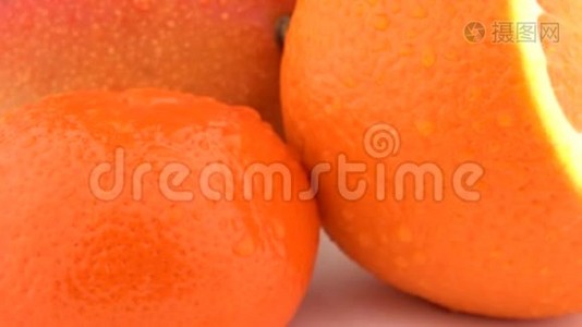 芒果、橙果和柑果的宏观，皮肤上有水滴。 在白色背景上旋转。 孤立无援。视频