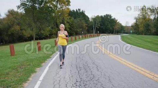 一个女人在一个漂亮整洁的公园里沿着小径慢跑。 前景，斯特朗姆视频